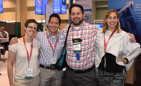 A group of four scientists pose for a picture in the exhibit hall.