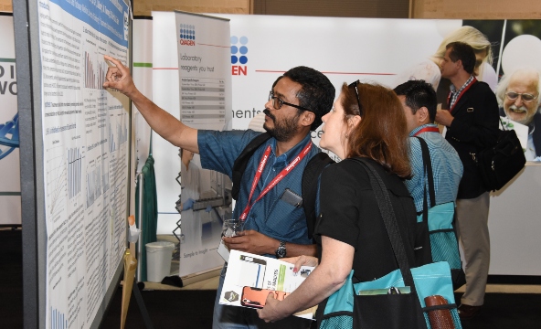 A scientist points to a graph while discussing a poster with a colleague at ASM CVS.