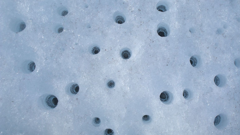 A pattern of holes that melted in a glacier.