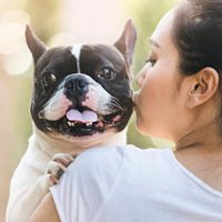 A young woman kisses her dog.