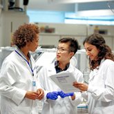 Three researchers huddle together in the lab.