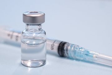 Vaccine vial next to a needle.