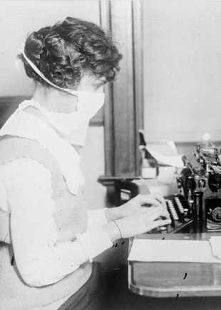 Woman working at a typewriter during 1918 flu pandemic.