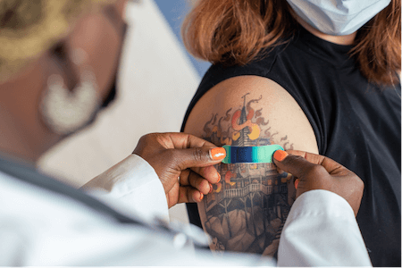 A health worker applies a bandage to the shoulder of a person who's just been vaccinated.