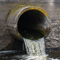 Water pours out of a cement pipe. 